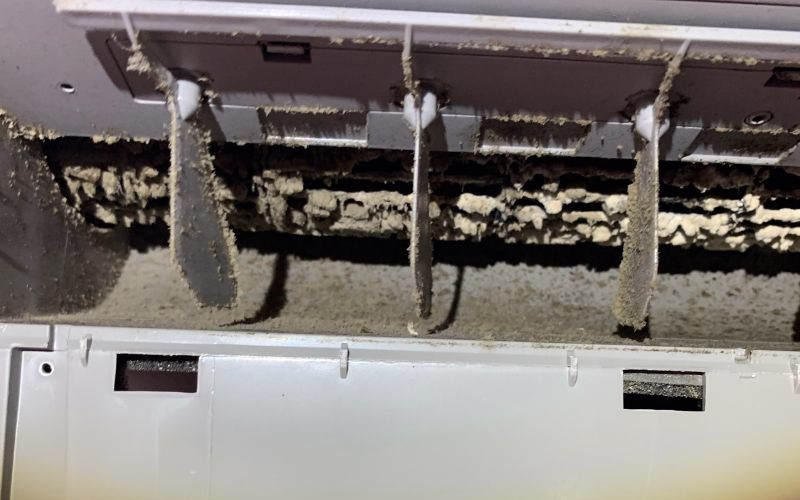 Heavily dirty split system aircon interior with dust and debris buildup on coils