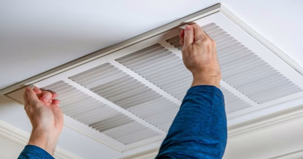 Technician removing ducted air conditioning return air grille for cleaning in Brisbane home
