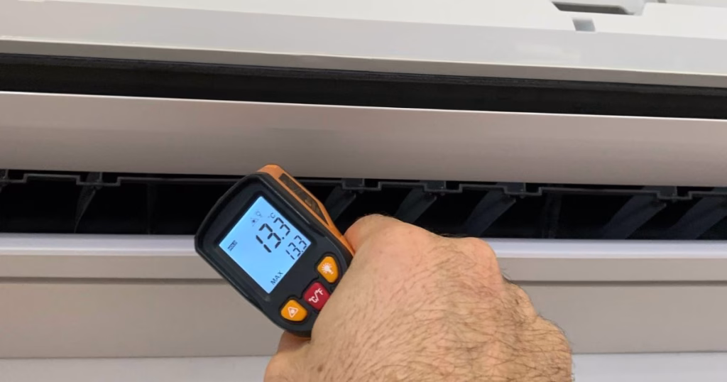 Aircon technician using infrared thermometer to check split system performance